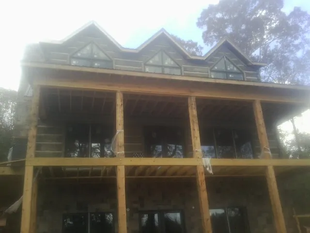 Dormers and porch framing on a large log home under construction — Roof Coating work by our crew in Chappell Hill