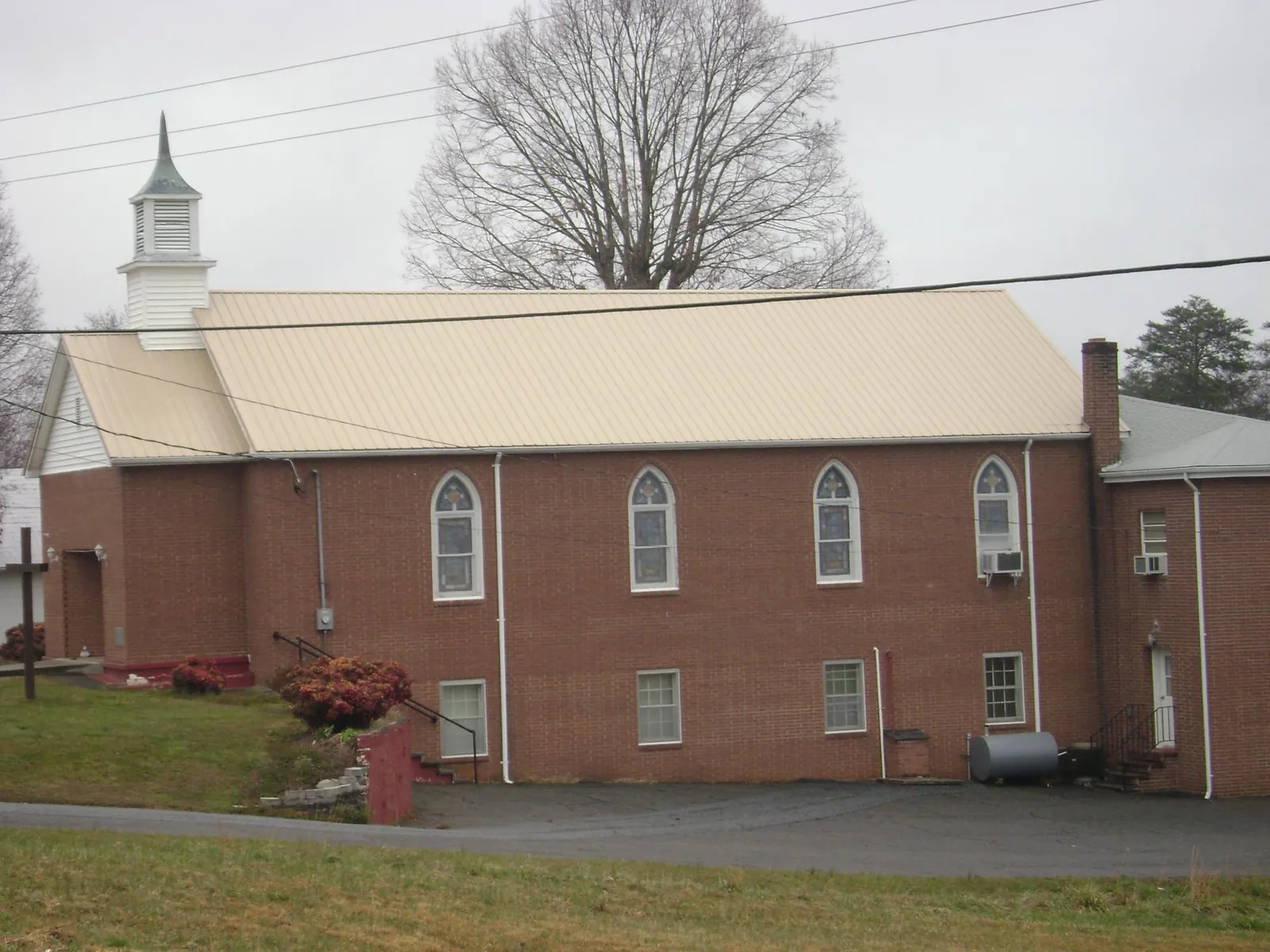 New tan metal roof on a brick church with a white steeple in Chappell Hill