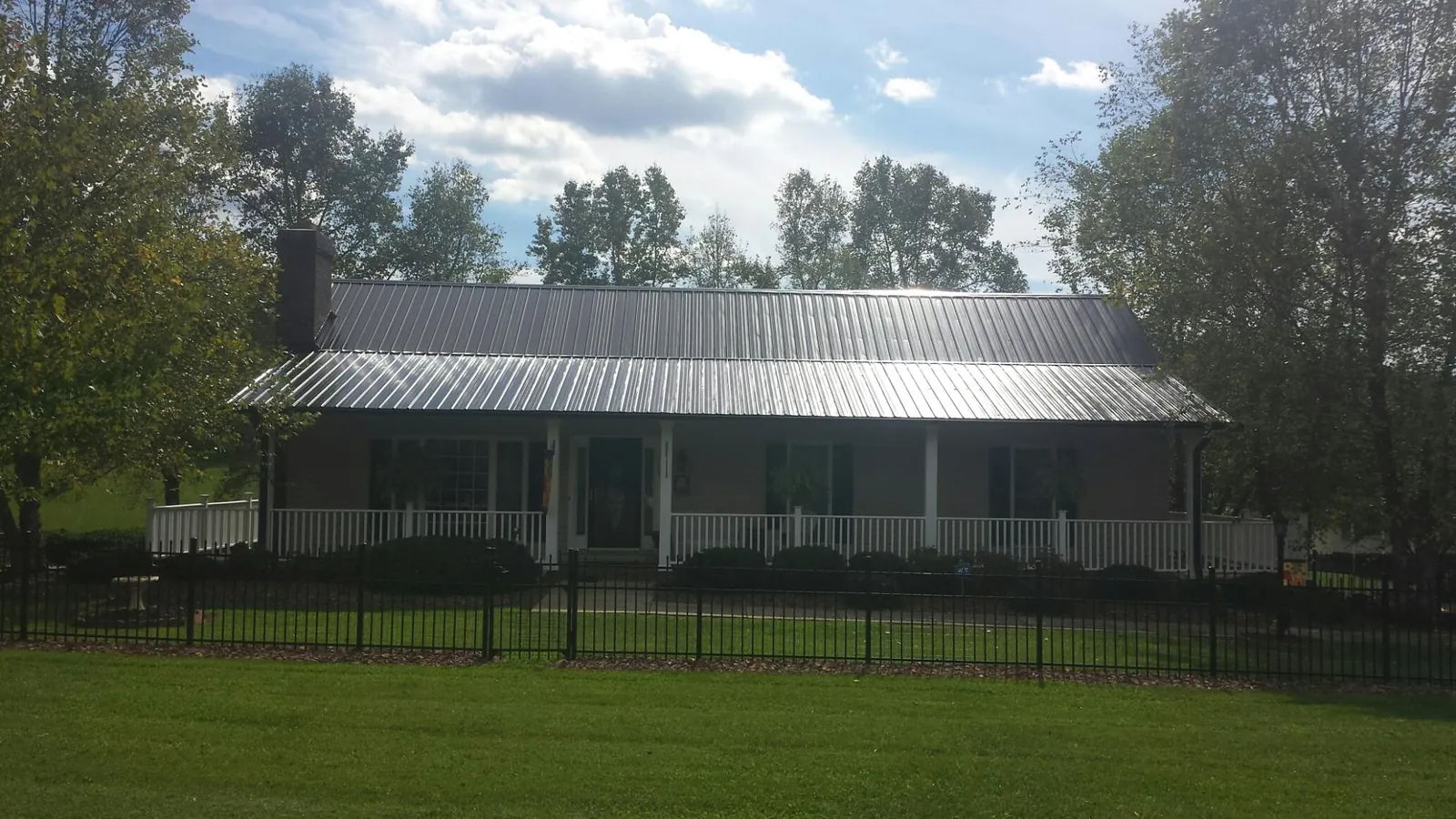 Gray metal roof on a brick ranch with a full width front porch — Gutter Guard Installation work by our crew in Chappell Hill
